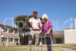 Doctor helping senior woman with her walker at outdoor nursing home