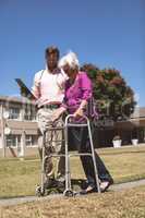 Doctor helping senior woman with her walker at backyard nursing home