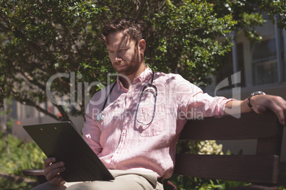 Confident male doctor holding medical report in backyard nursing home