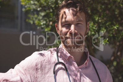 Confident male doctor sitting on bench outside the nursing home