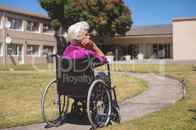 Senior woman relaxing on wheelchair at nursing home park