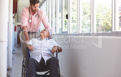 Male doctor pushing senior wheelchair man