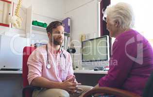 Male doctor and senior woman interacting with each other in clinic