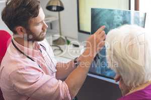 Male doctor and senior female patient discussing over x ray in clinic