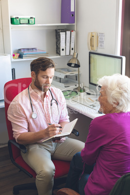 Male doctor writing prescription to senior woman in clinic