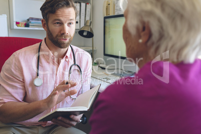 Male doctor writing prescription to senior woman in clinic