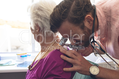 Male dermatologist examining senior patient through dermatoscopy