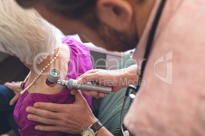 Male dermatologist examining senior patient through dermatoscopy