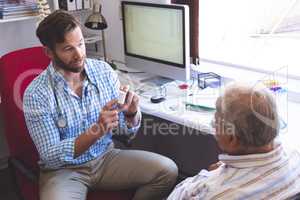 Male doctor prescribing pills to his senior male patient in clinic