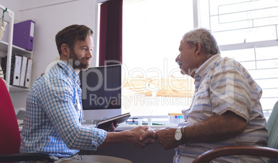 Male doctor and senior man interacting with each other in clinic
