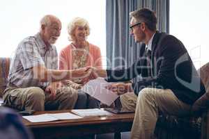 Male physician interacting with senior couple at retirement home