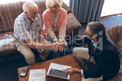 Male physician and senior couple discussing over laptop