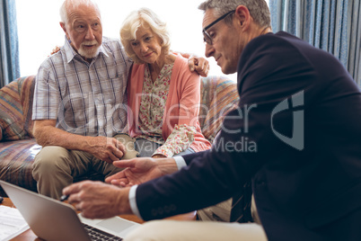 Male physician discussing over the laptop with senior couple at retirement home