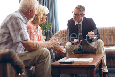 Male physician interacting with senior couple at retirement home