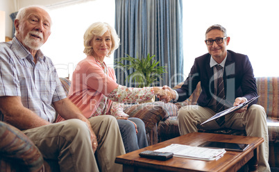 Matured male physician shaking hand and smiling at retirement home