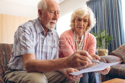 Senior couple looking at bill  while sitting