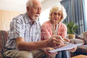 Senior couple looking at bill  while sitting