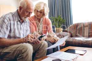 Senior couple calculating bill while sitting at retirement home