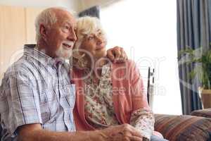 Senior couple sitting and posing on sofa at retirement home