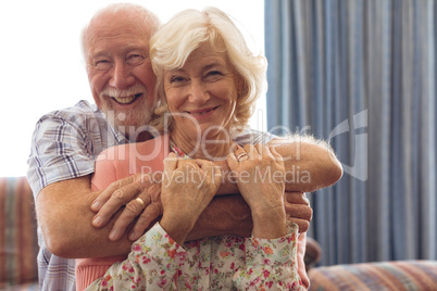 Happy senior couple sitting on sofa at retirement home