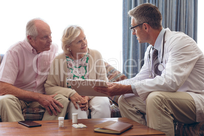 Male doctor interacting with senior couple at retirement home