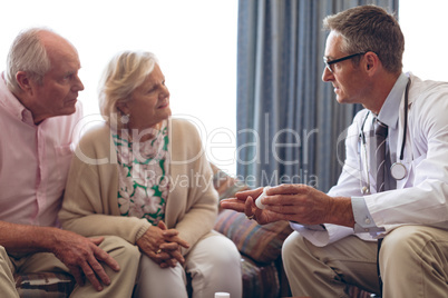 Male doctor prescription medicine to senior couple at retirement home