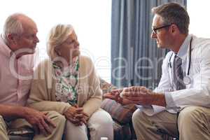 Male doctor prescription medicine to senior couple at retirement home