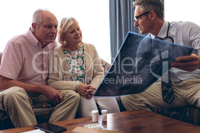 Male doctor discussing over x ray with senior couple