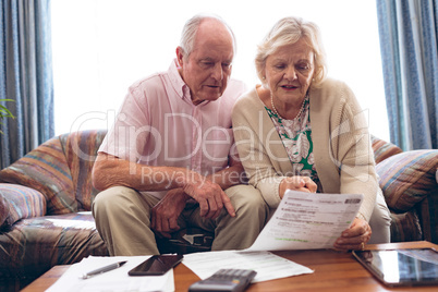 Couple discussing over medical bill  while sitting on sofa