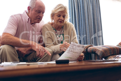 Couple discussing over medical bill while sitting on sofa