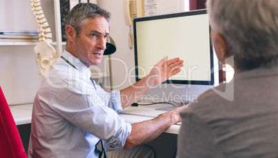Doctor discussing over computer with senior woman