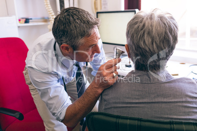 Male doctor checking senior female patient in clinic