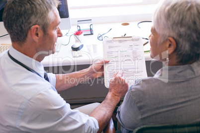 Male doctor showing medical report to the senior female patient
