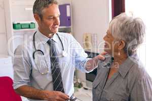 Confident male doctor interacting with senior female patient in clinic