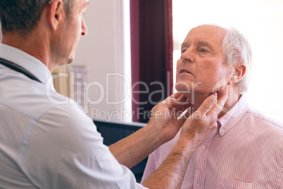 Matured male doctor checking senior man in clinic