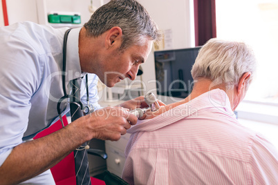 Male dermatologist examining senior patient with dermatoscopy
