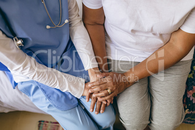 Female doctor holding hand of senior patient