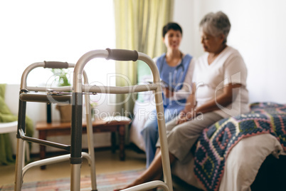 Female doctor interacting with senior female patient at retirement home