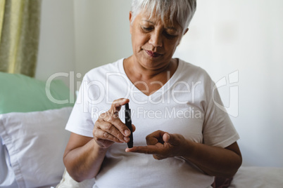 Female senior patient checking blood sugar level with glucometer