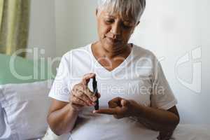 Female senior patient checking blood sugar level with glucometer