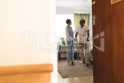 Female nurse talking with senior man while walking with walker