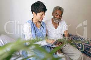 Female doctor and senior male patient using digital tablet at retirement home