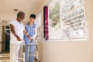 Female nurse helping senior male patient to walk with walker