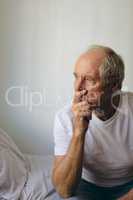 Senior male patient sitting on bed at retirement home
