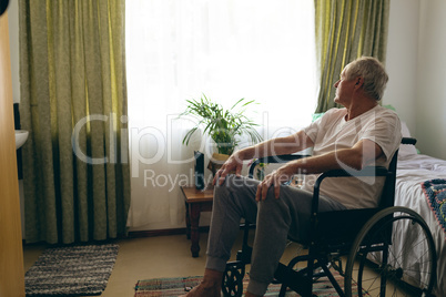 Male patient  looking outside the window while sitting in wheelchair