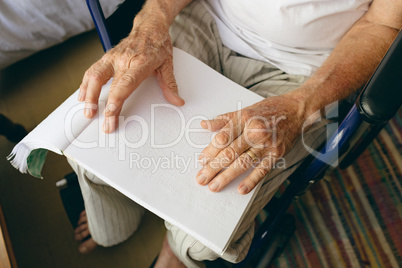 Senior male patient is reading braille in a retirement home