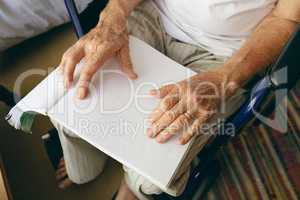Senior male patient is reading braille in a retirement home