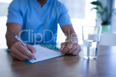Male surgeon writing on medical chart