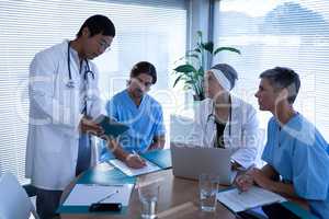 Surgeons discussing over digital tablet in clinic at hospital