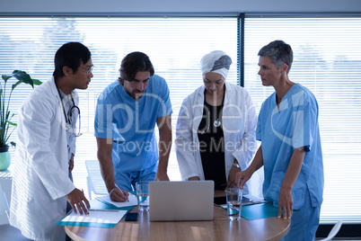 Doctors discussing over laptop in clinic at hospital